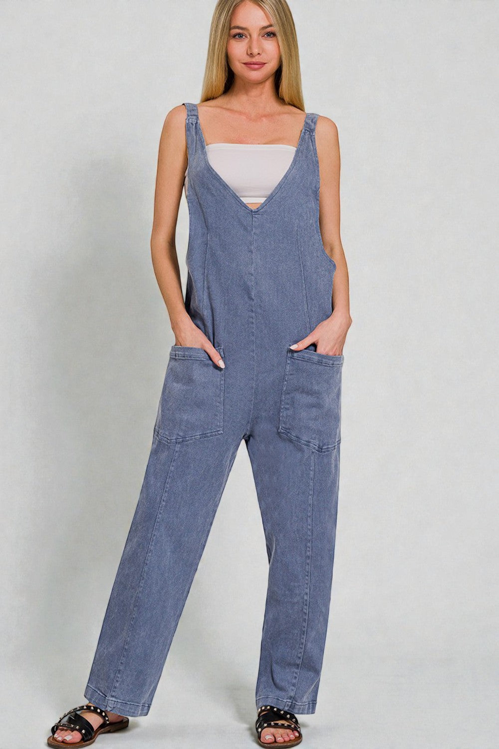 Woman wearing a denim jumpsuit against a plain background