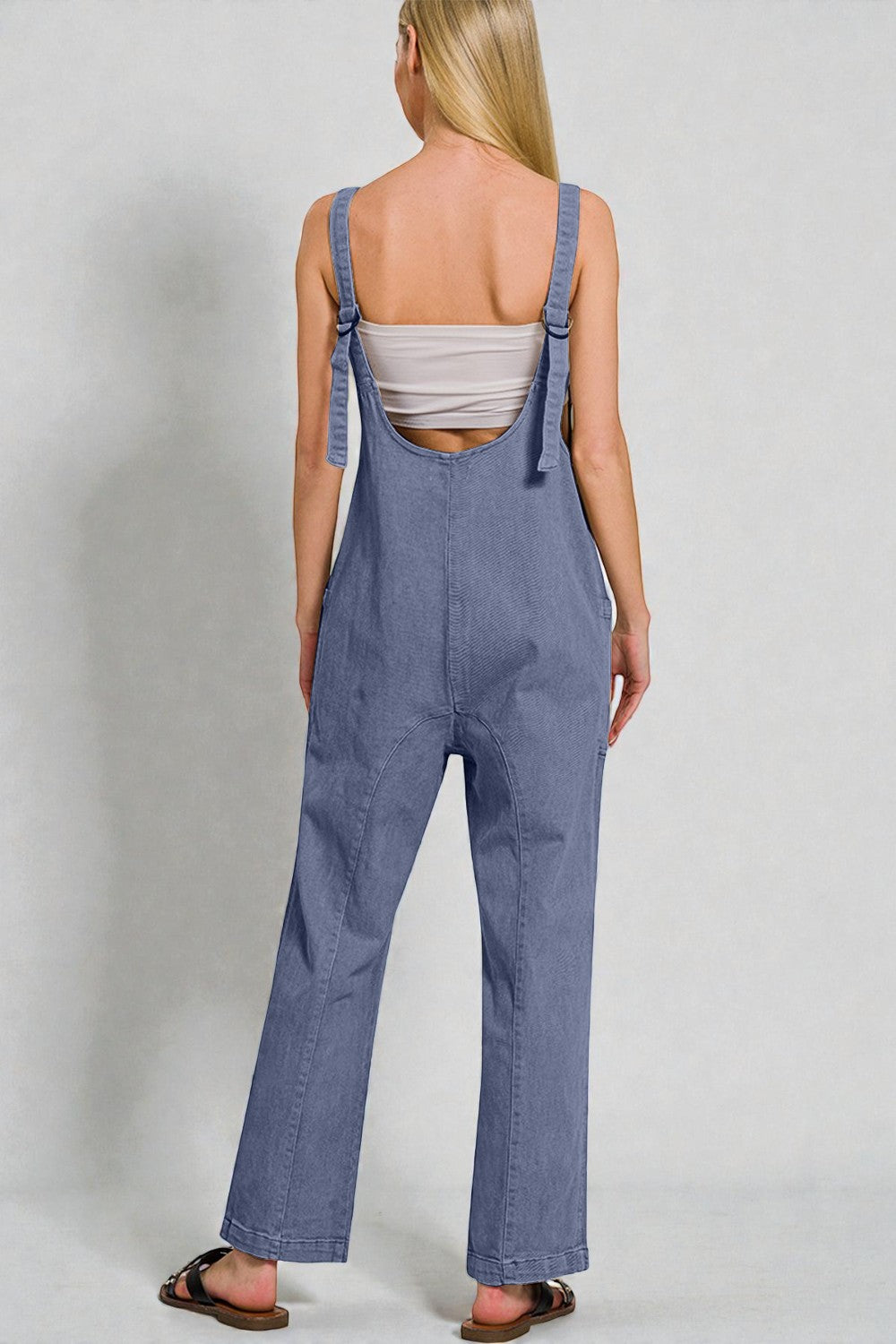 Person wearing blue denim overalls on a plain background