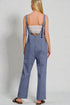 Person wearing blue denim overalls on a plain background
