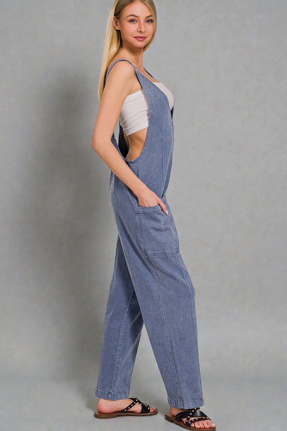 Woman wearing blue denim overalls against a gray background