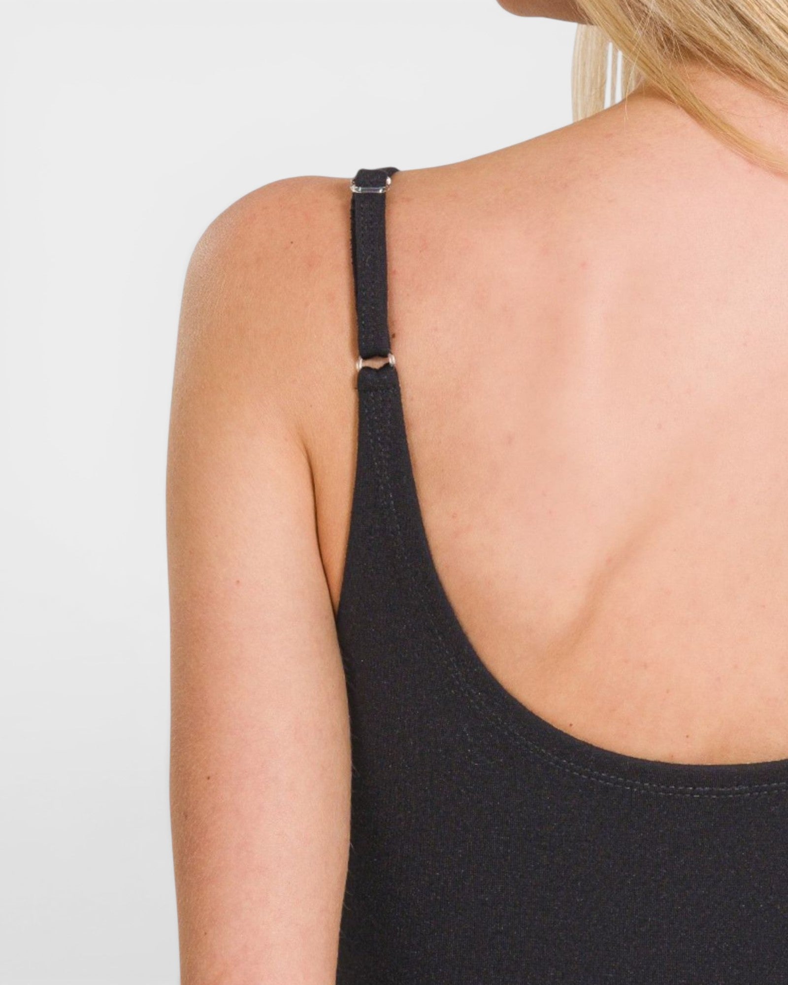 Black tank top with thin straps worn by a person on a light gray background