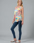 Woman wearing a colorful patterned top and blue jeans on a gray background