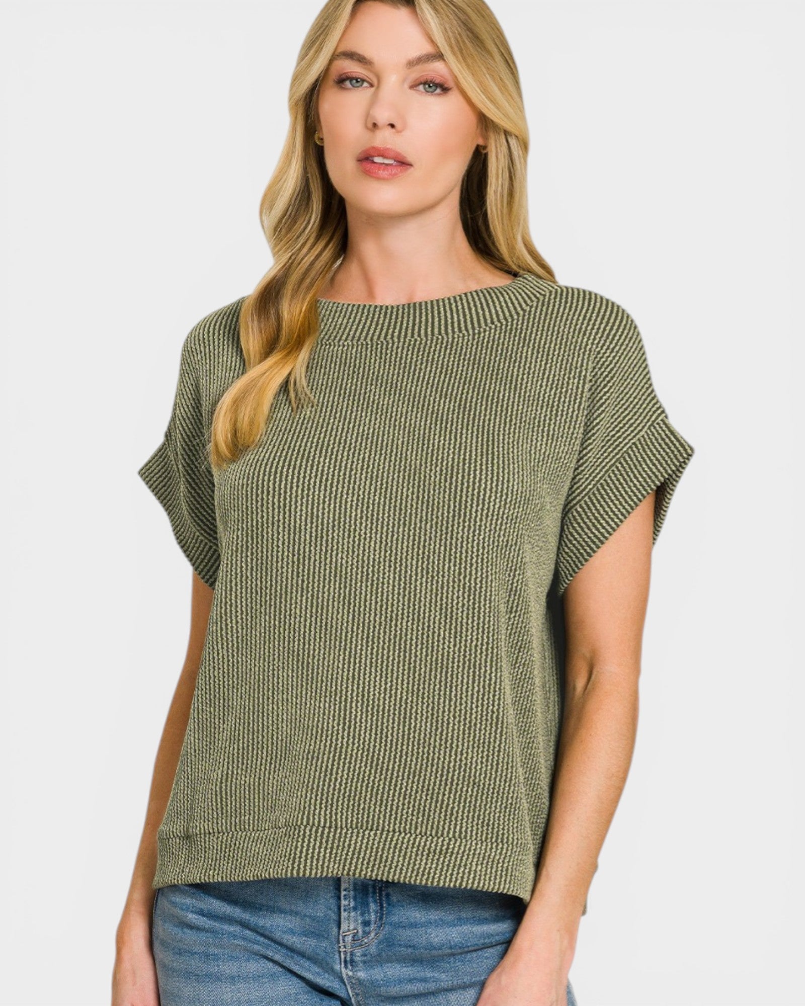 Woman wearing a green ribbed sweater and blue jeans on a white background