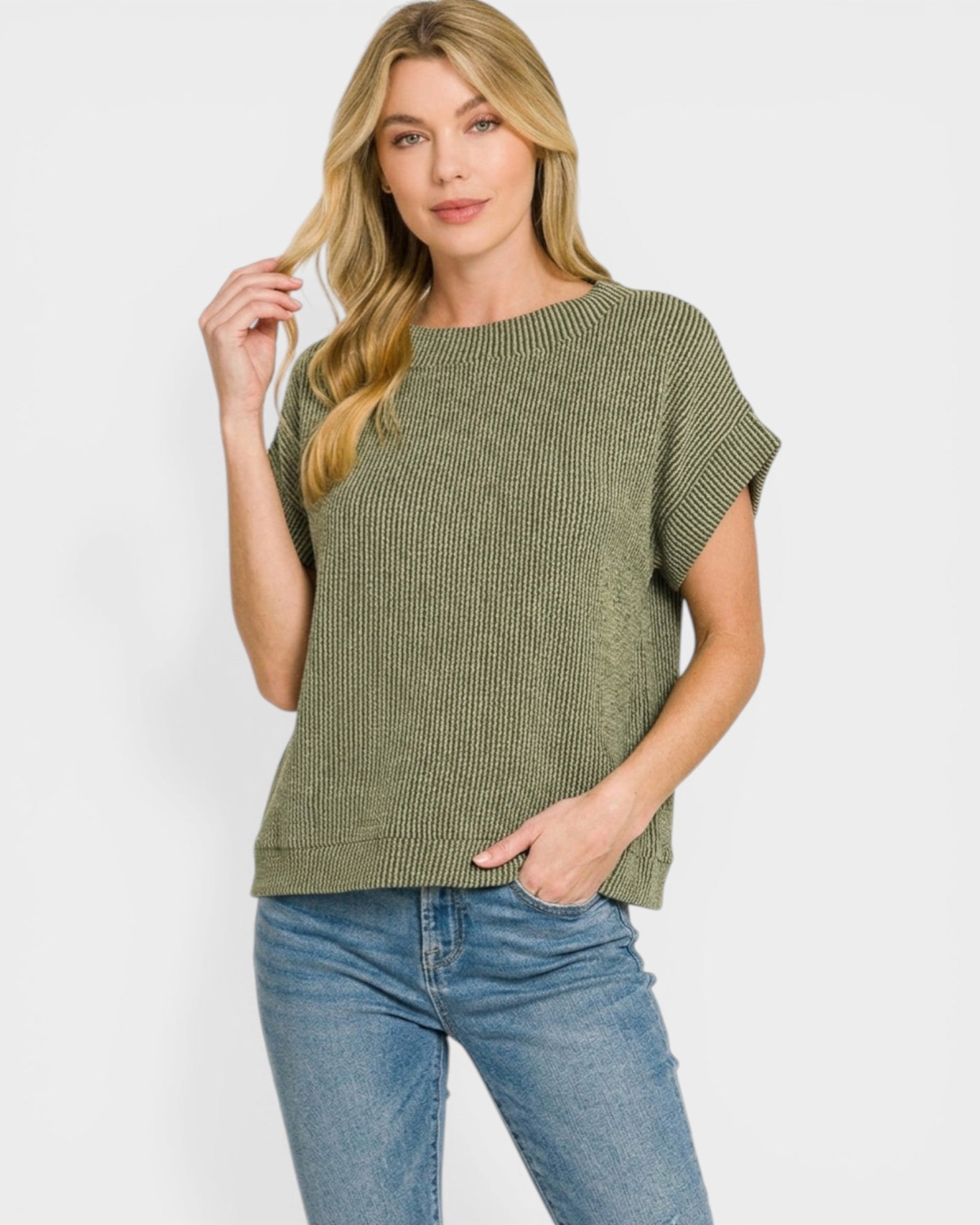 Woman wearing a green ribbed sweater and blue jeans on a white background