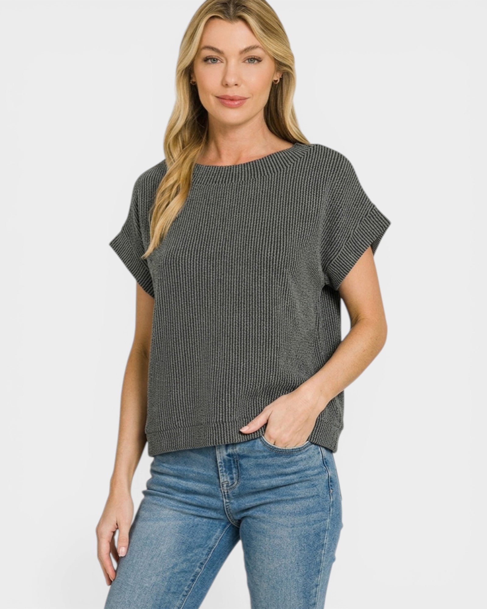 Woman wearing a gray ribbed sweater and blue jeans on a white background