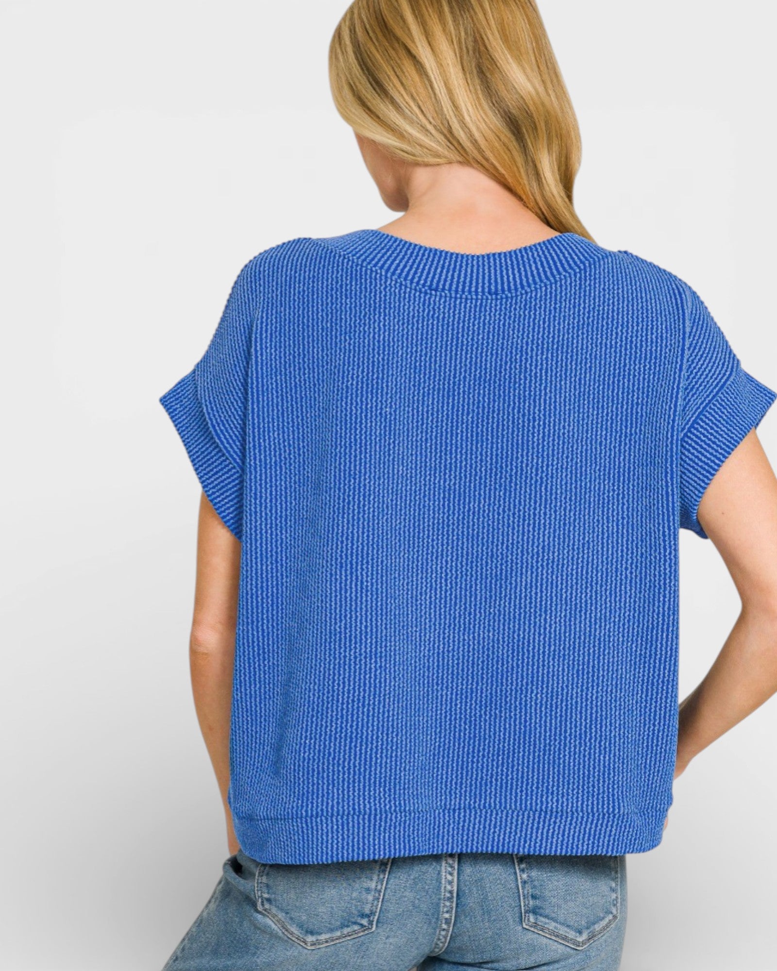 Person wearing a blue ribbed sweater on a white background