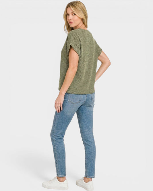 Woman wearing a green top and blue jeans on a white background