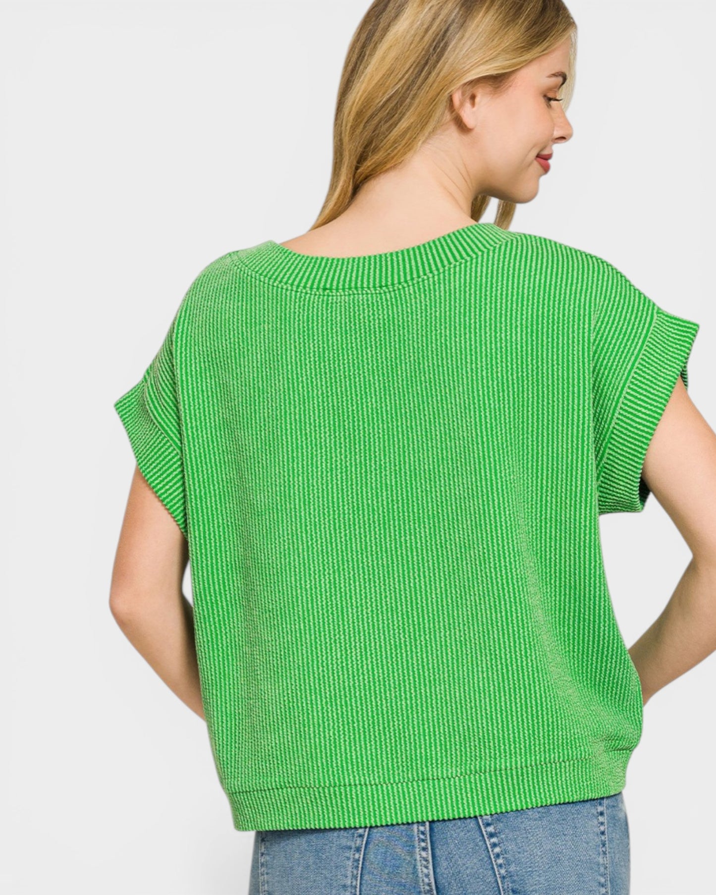 Woman wearing a green sweater against a plain background