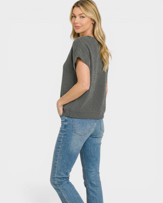 Woman wearing a gray knit top and blue jeans on a white background