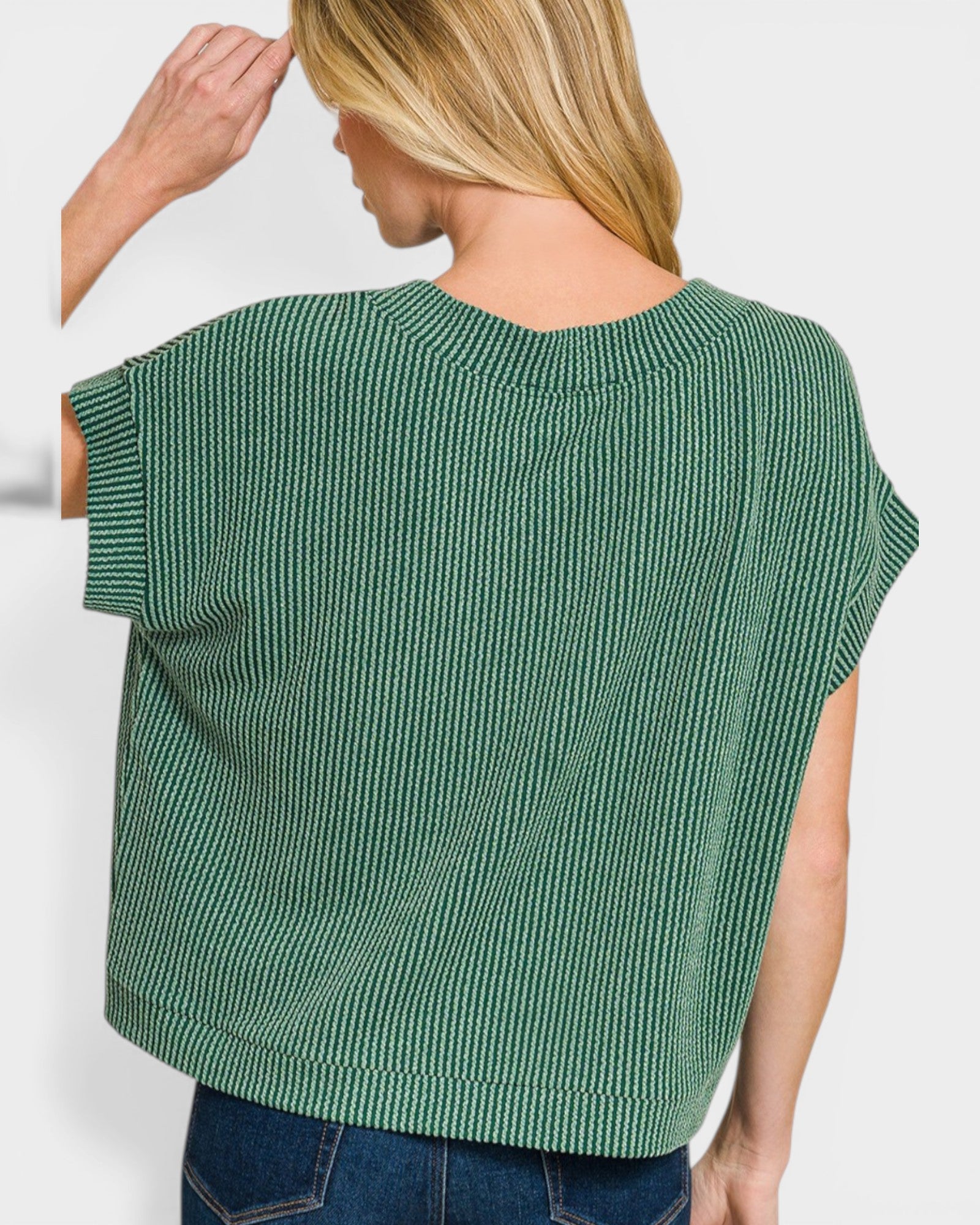 Green knitted top worn by a person on a white background