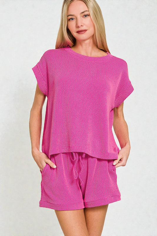 Woman wearing a pink textured outfit with shorts on a white background