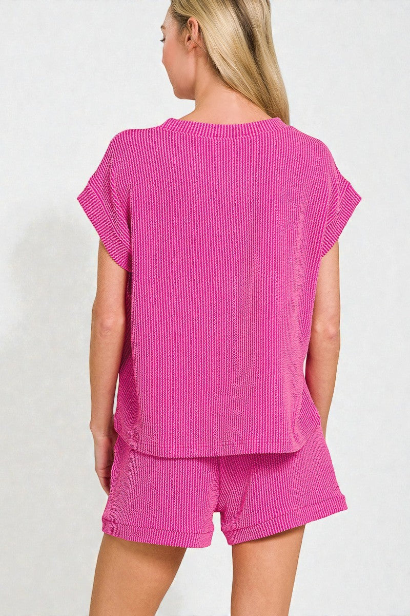 Woman wearing a pink textured top and shorts set on a white background