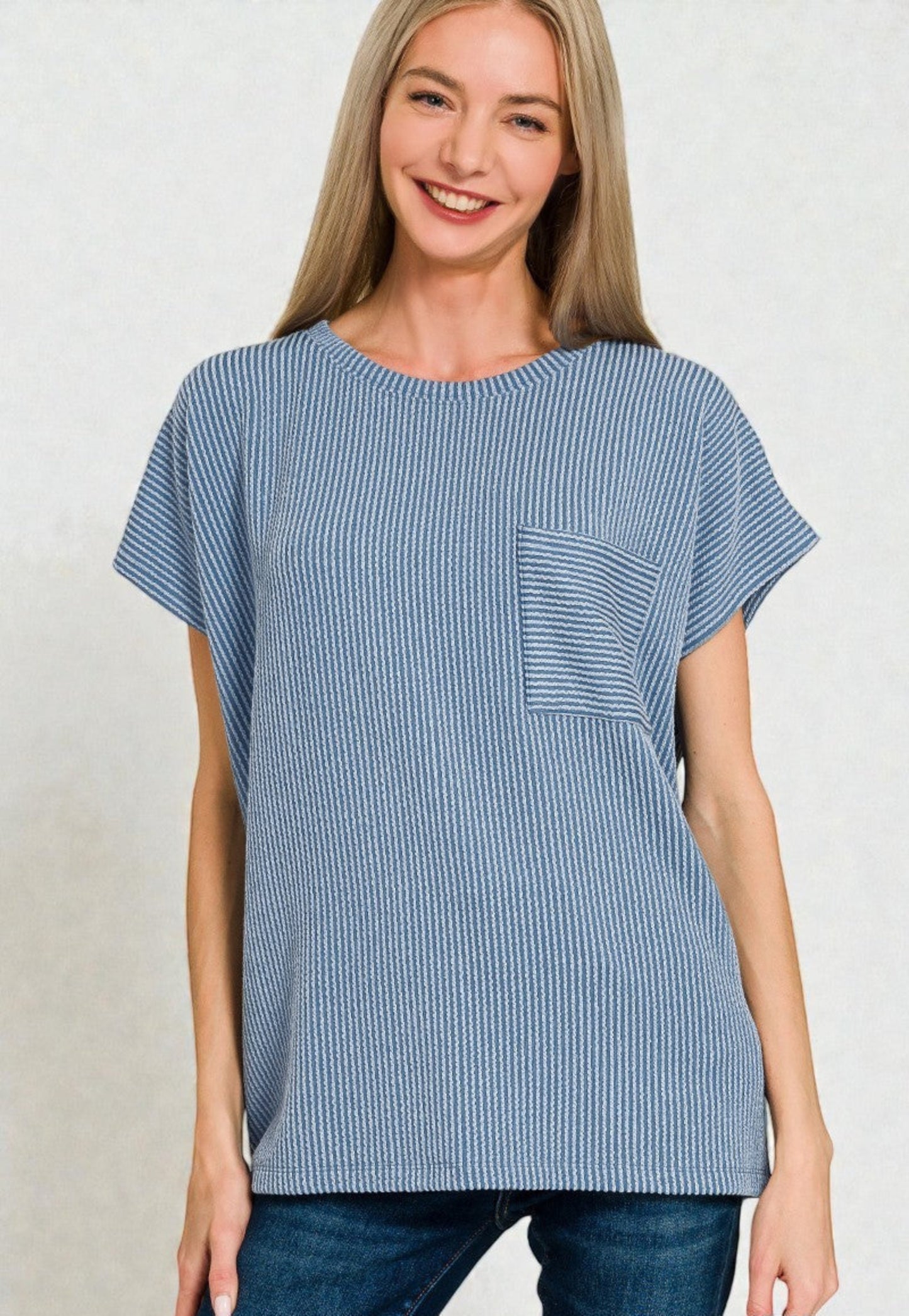 Woman wearing a blue striped tunic with a pocket on a plain background