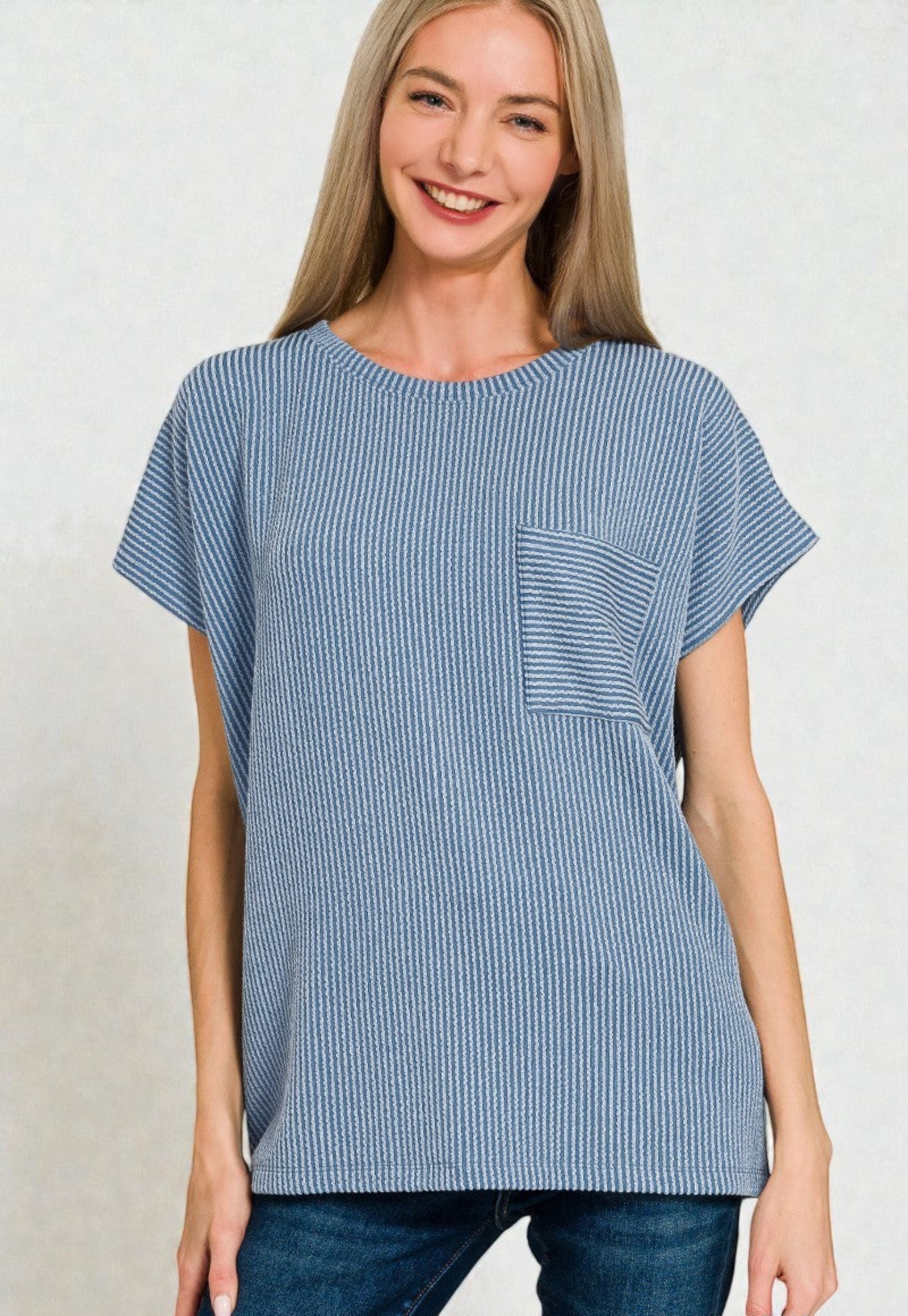 Woman wearing a blue striped tunic with a pocket on a plain background