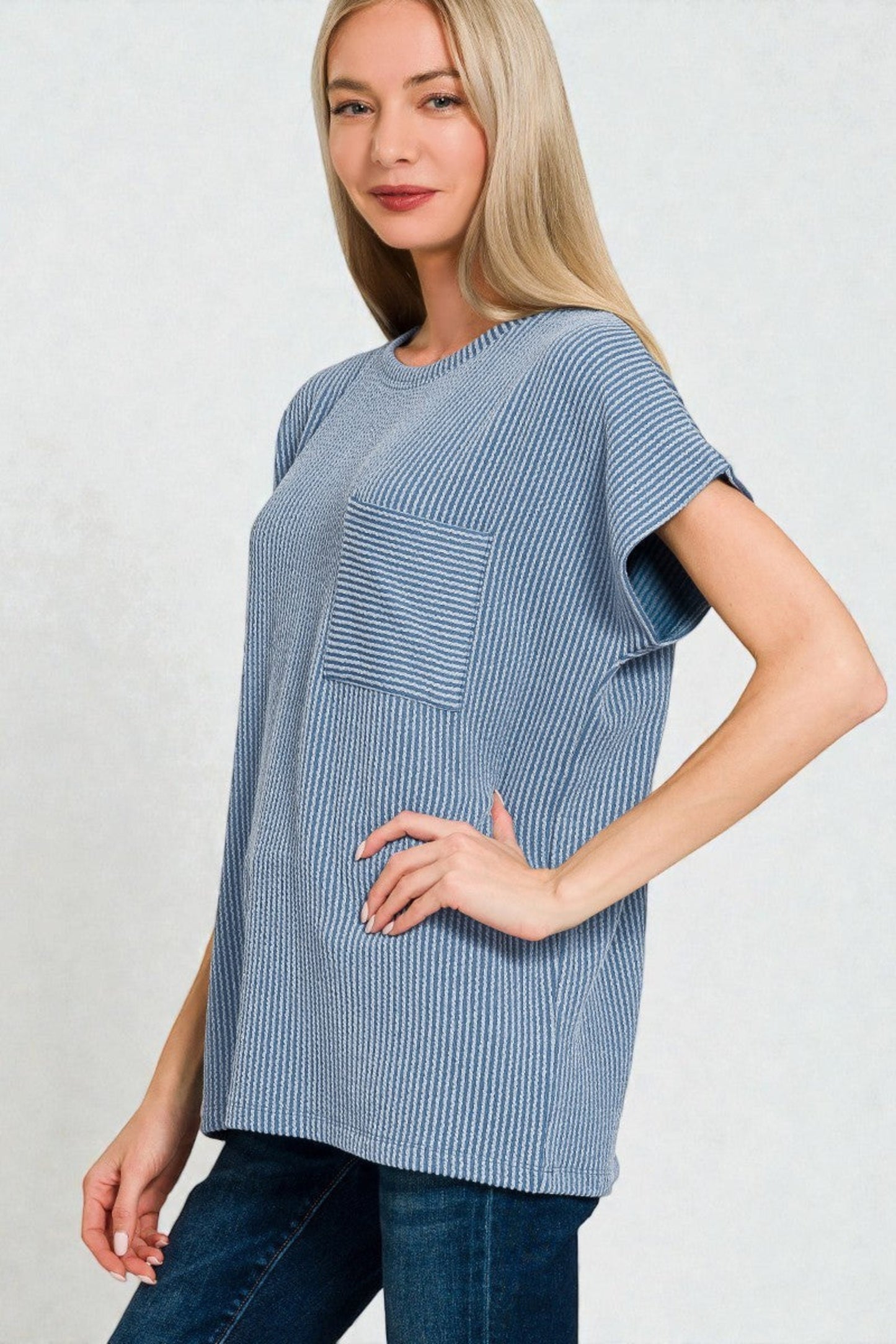 Woman wearing a blue striped shirt with a pocket on a light gray background