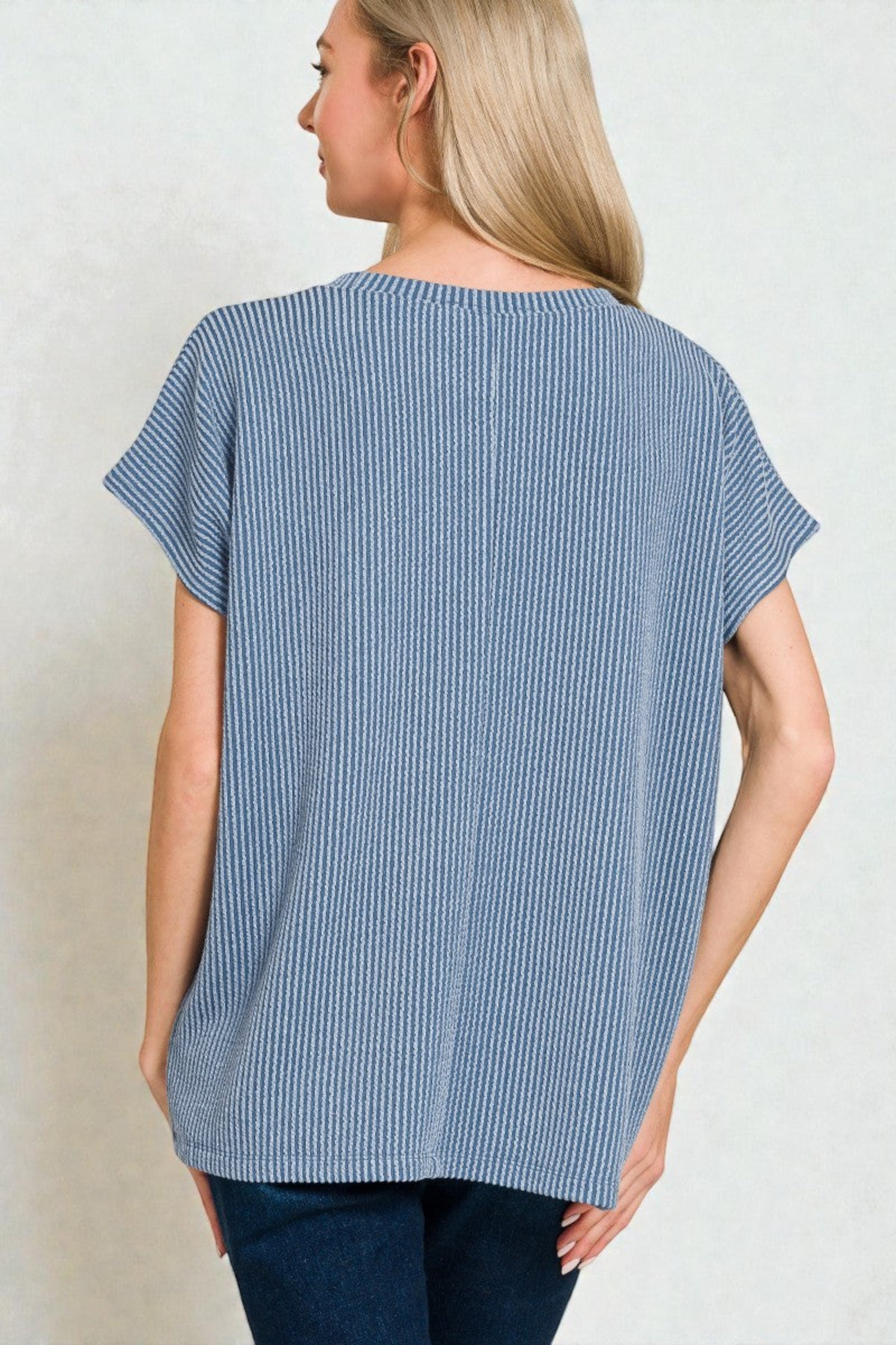 Woman wearing a blue striped shirt from behind on a plain background