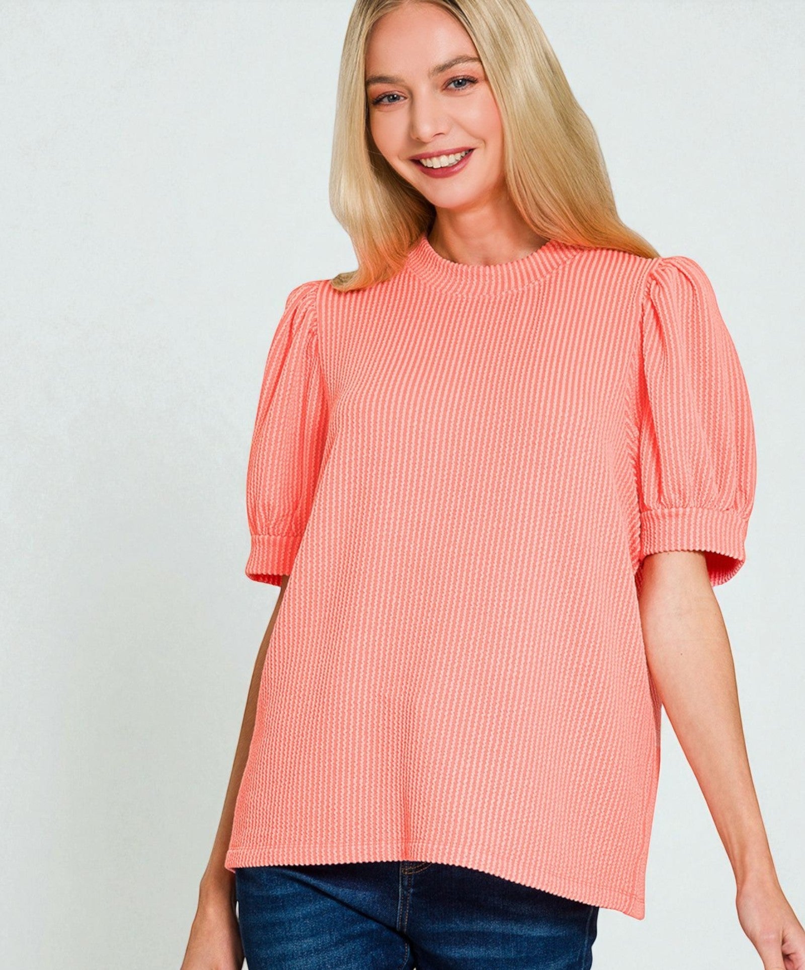 Woman wearing a coral pink blouse with puff sleeves on a white background