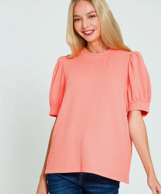 Woman wearing a coral pink blouse with puff sleeves on a white background