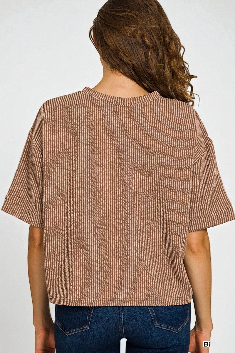 Woman wearing a brown textured top and blue jeans on a white background