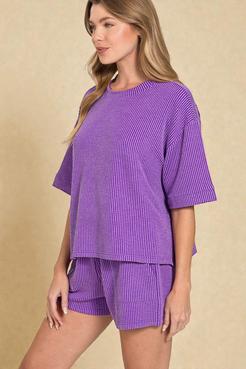 Woman wearing a purple ribbed outfit on a beige background