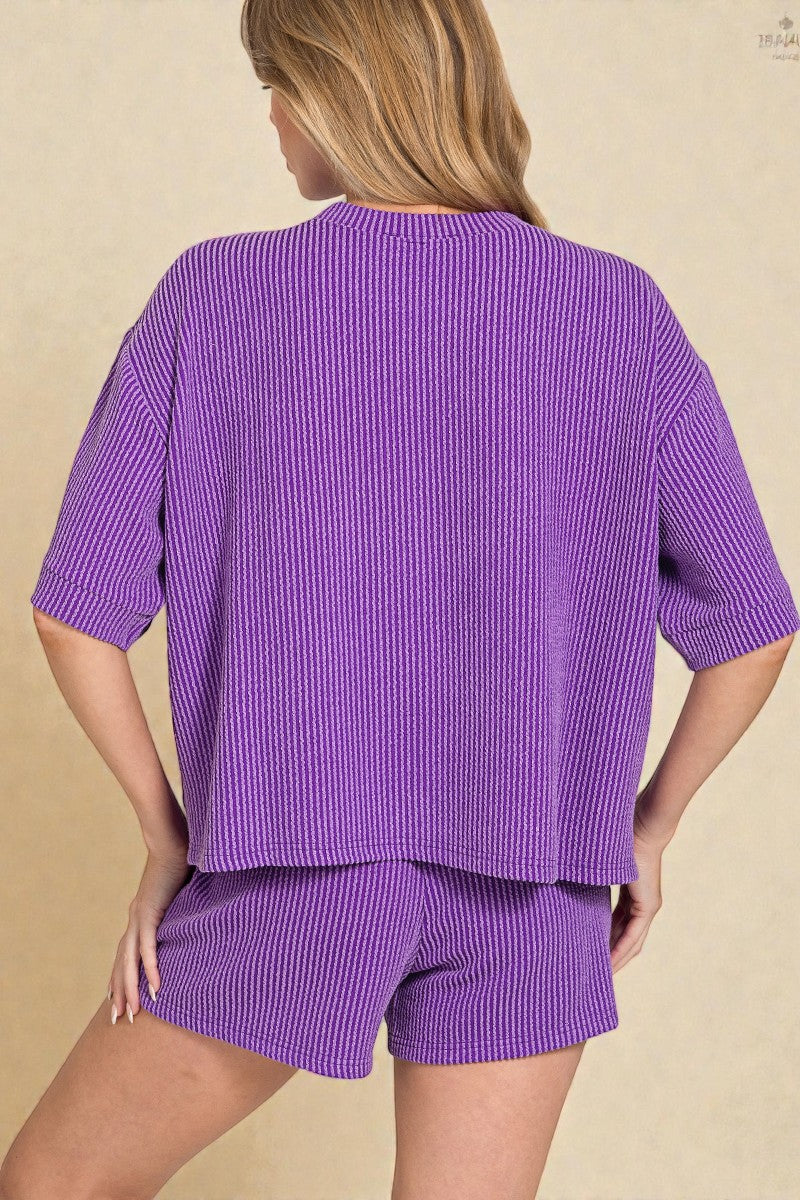 Person wearing a purple ribbed outfit on a beige background