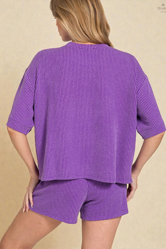 Person wearing a purple ribbed outfit on a beige background