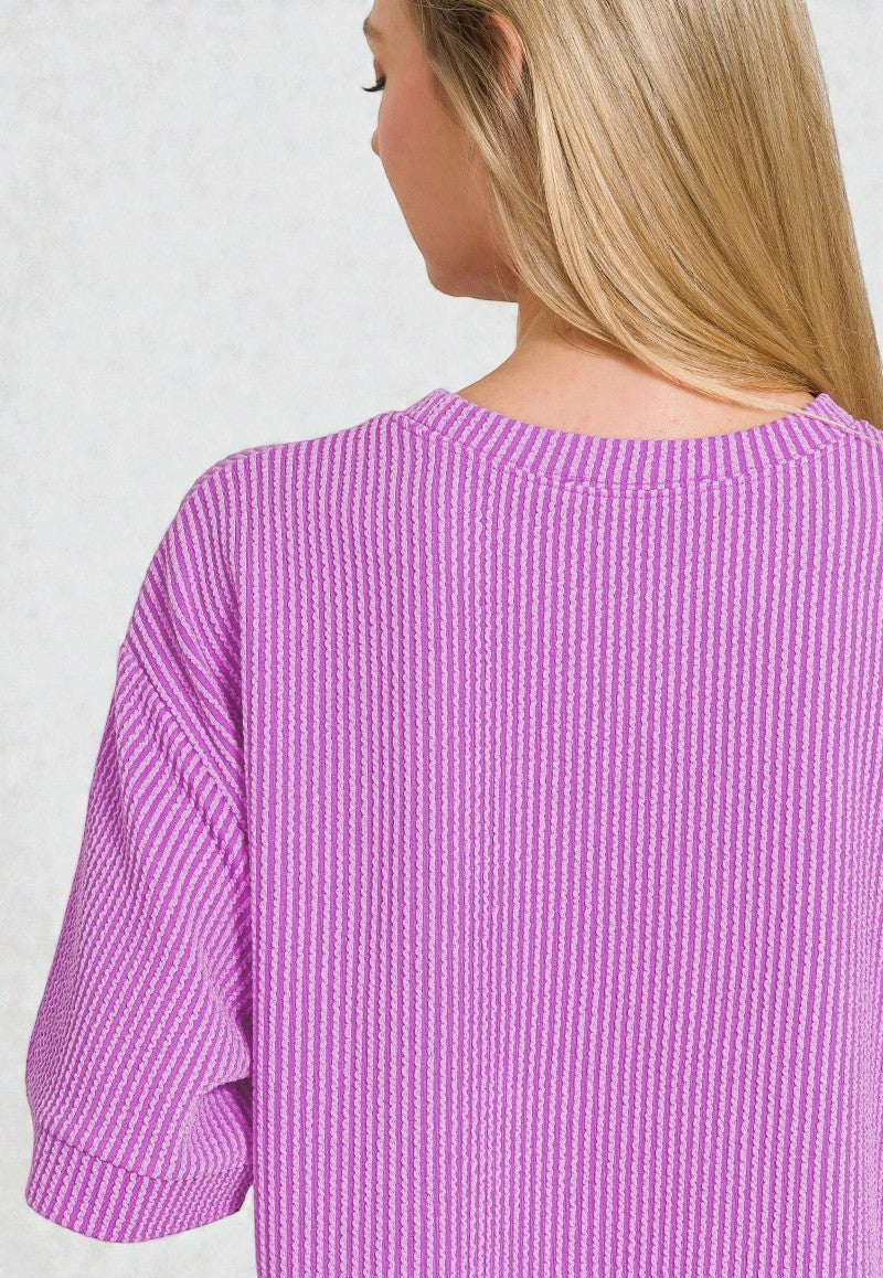 Purple textured top worn by a person on a plain background