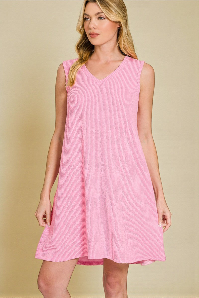 Woman wearing a pink sleeveless dress against a beige background