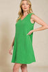 Woman wearing a green sleeveless dress against a beige background
