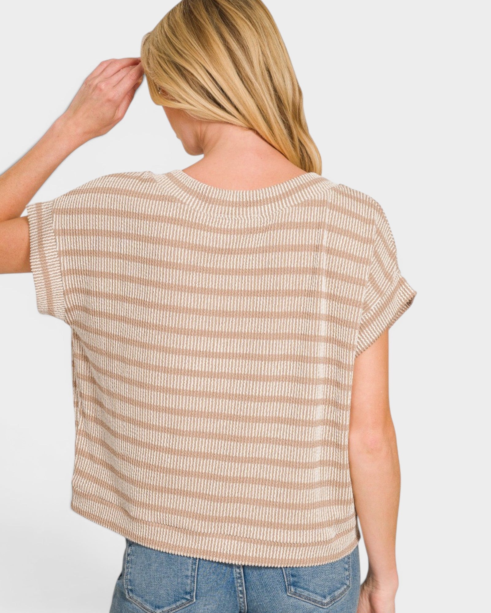 Woman wearing a beige and white striped shirt with a plain background