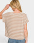 Woman wearing a beige and white striped shirt with a plain background
