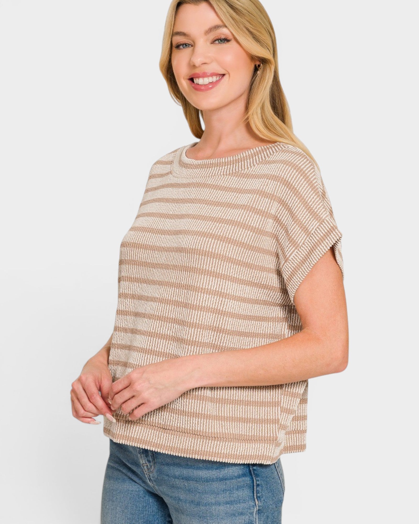 Woman wearing a beige and brown striped top against a white background