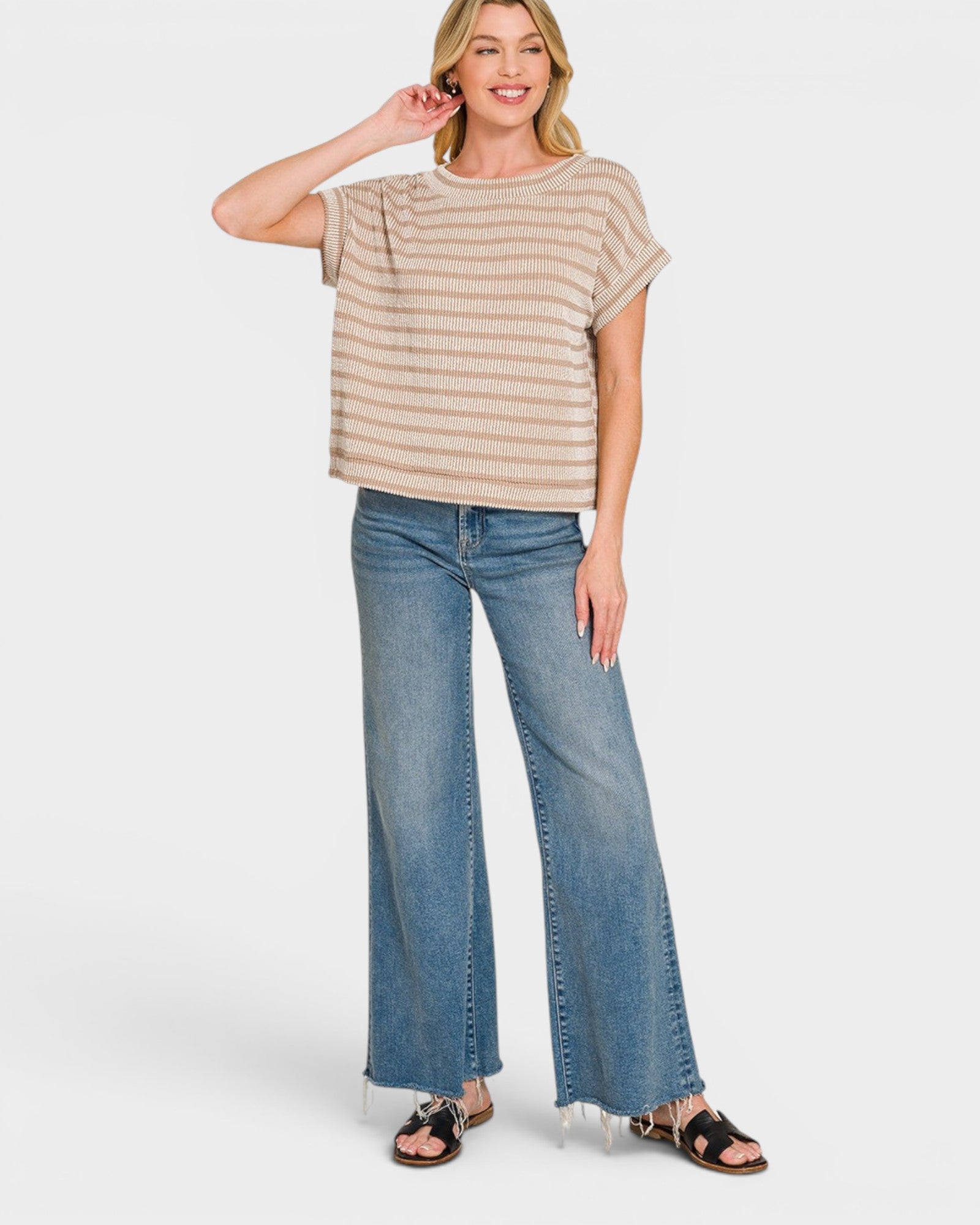 Woman wearing a striped shirt and blue jeans on a white background