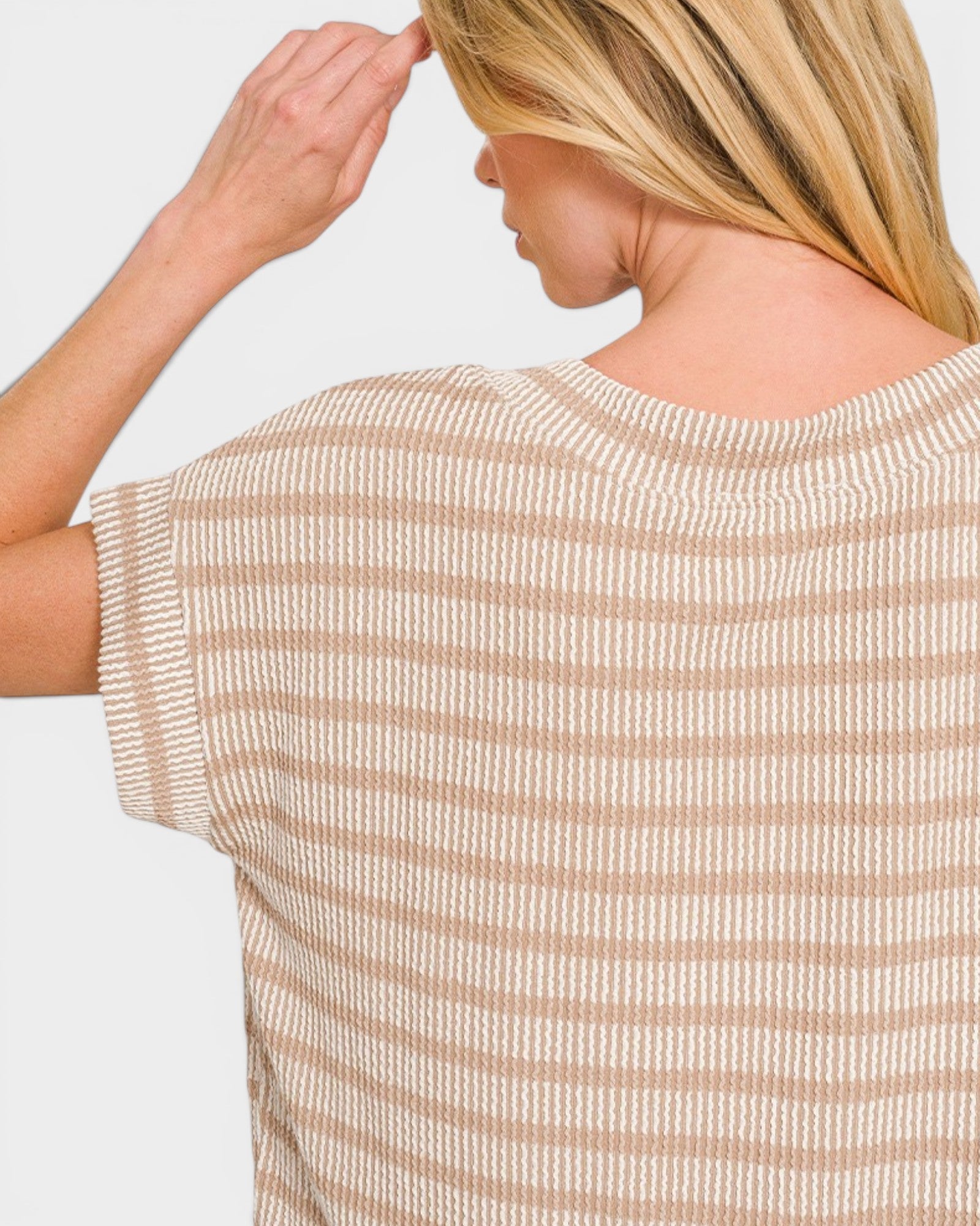 Woman wearing a beige and white striped shirt against a light gray background