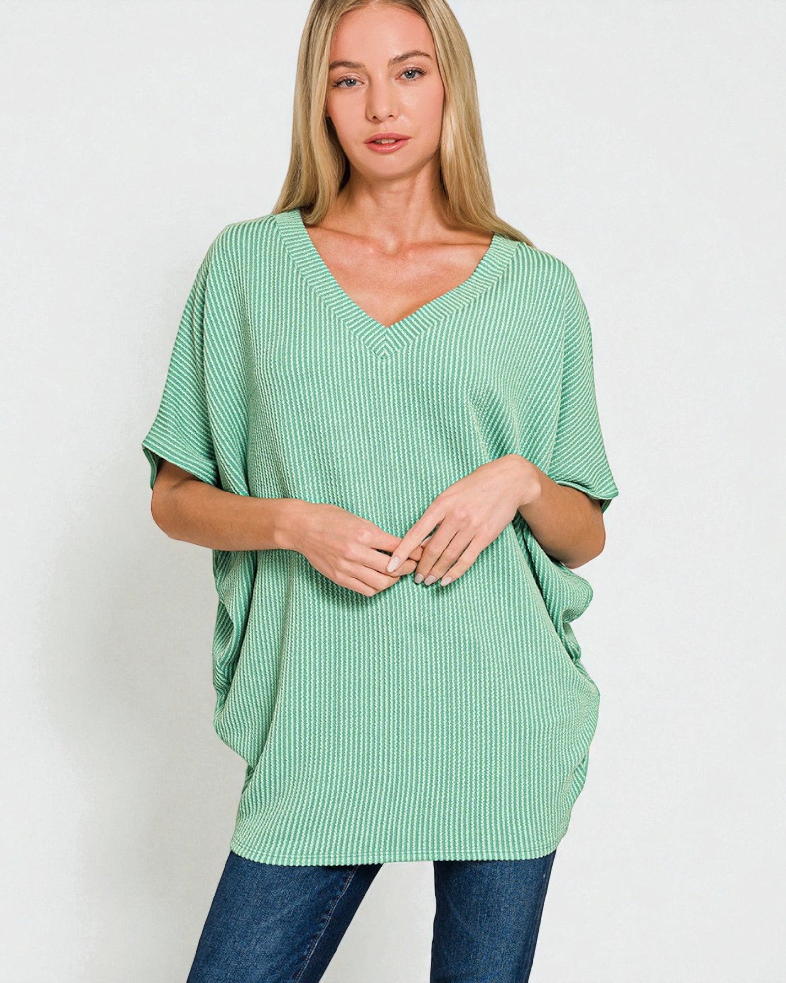 Woman wearing a green ribbed sweater against a white background