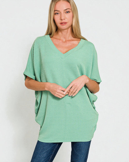 Woman wearing a green ribbed sweater against a white background