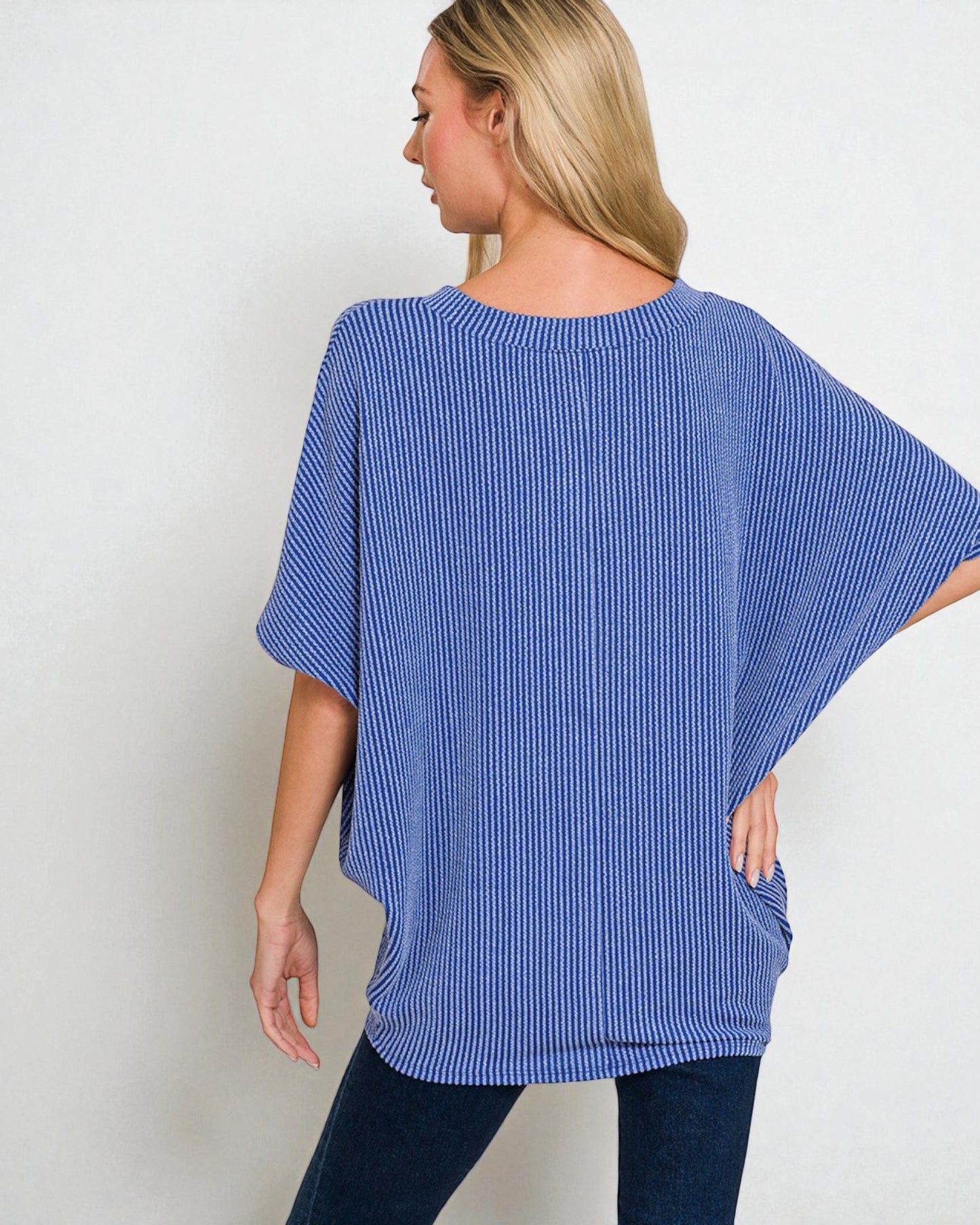 Woman wearing a blue striped oversized top against a plain background