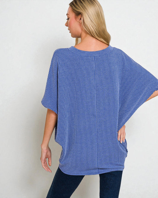 Woman wearing a blue striped oversized top against a plain background