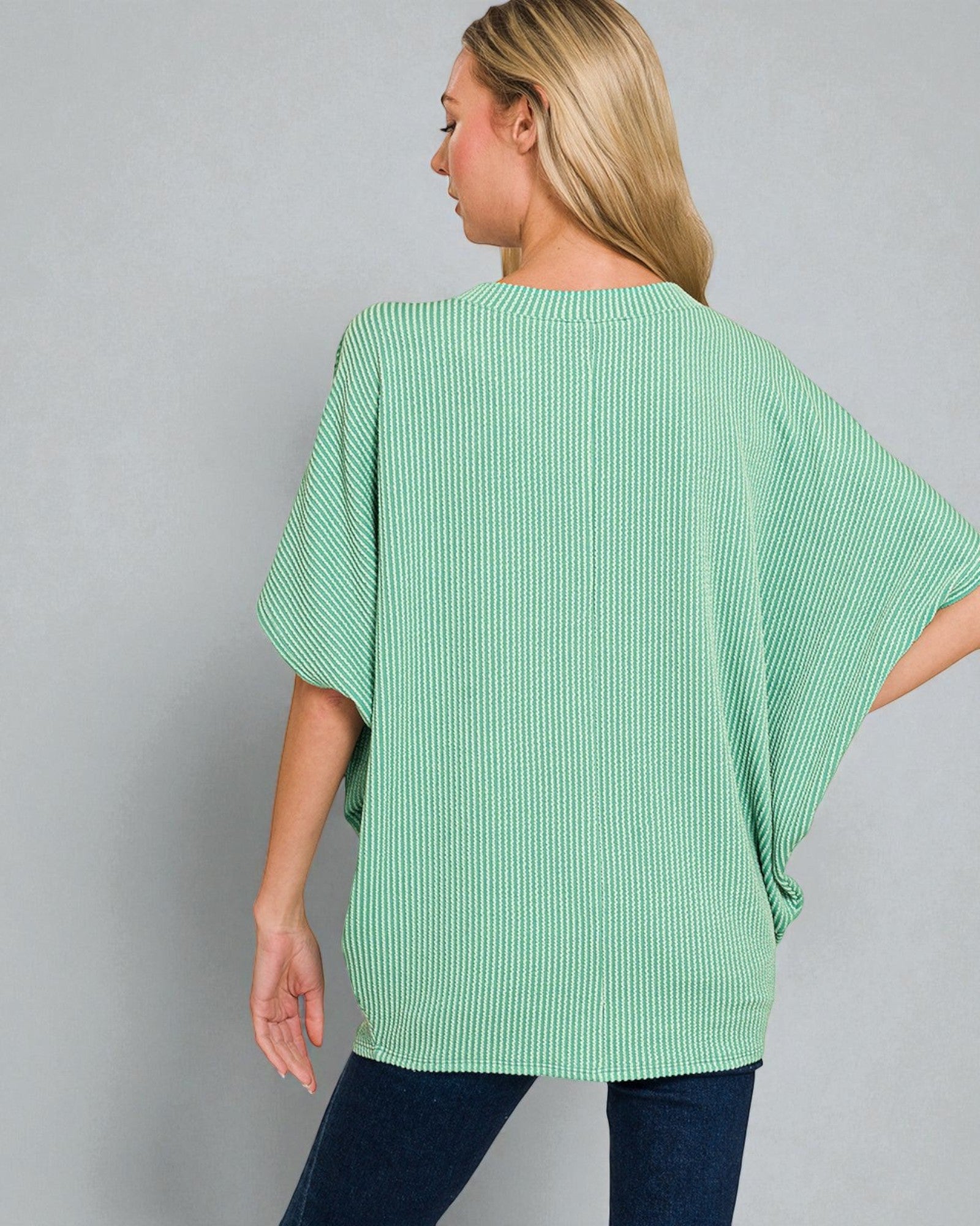 Woman wearing a green ribbed sweater against a gray background