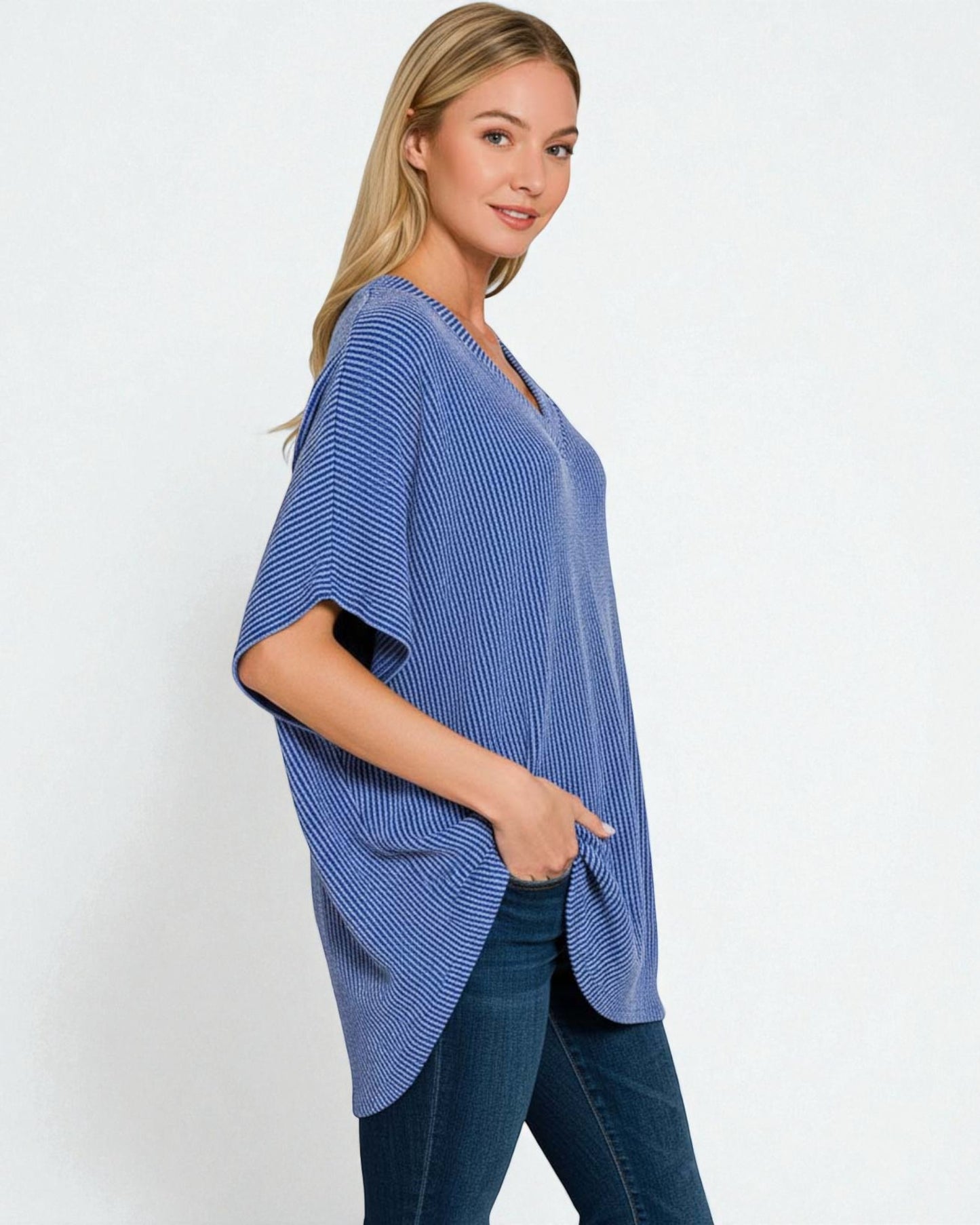 Woman wearing a blue poncho over a black top on a white background