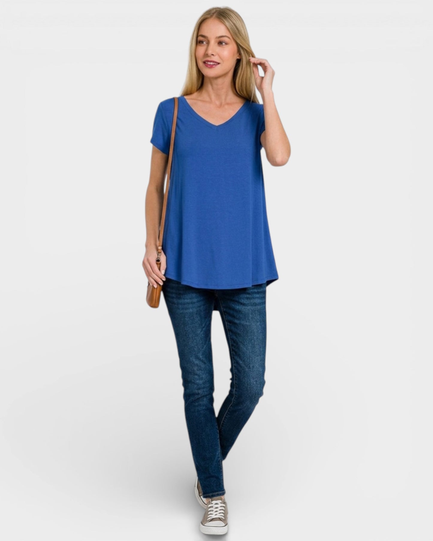Woman wearing a blue top and jeans on a white background
