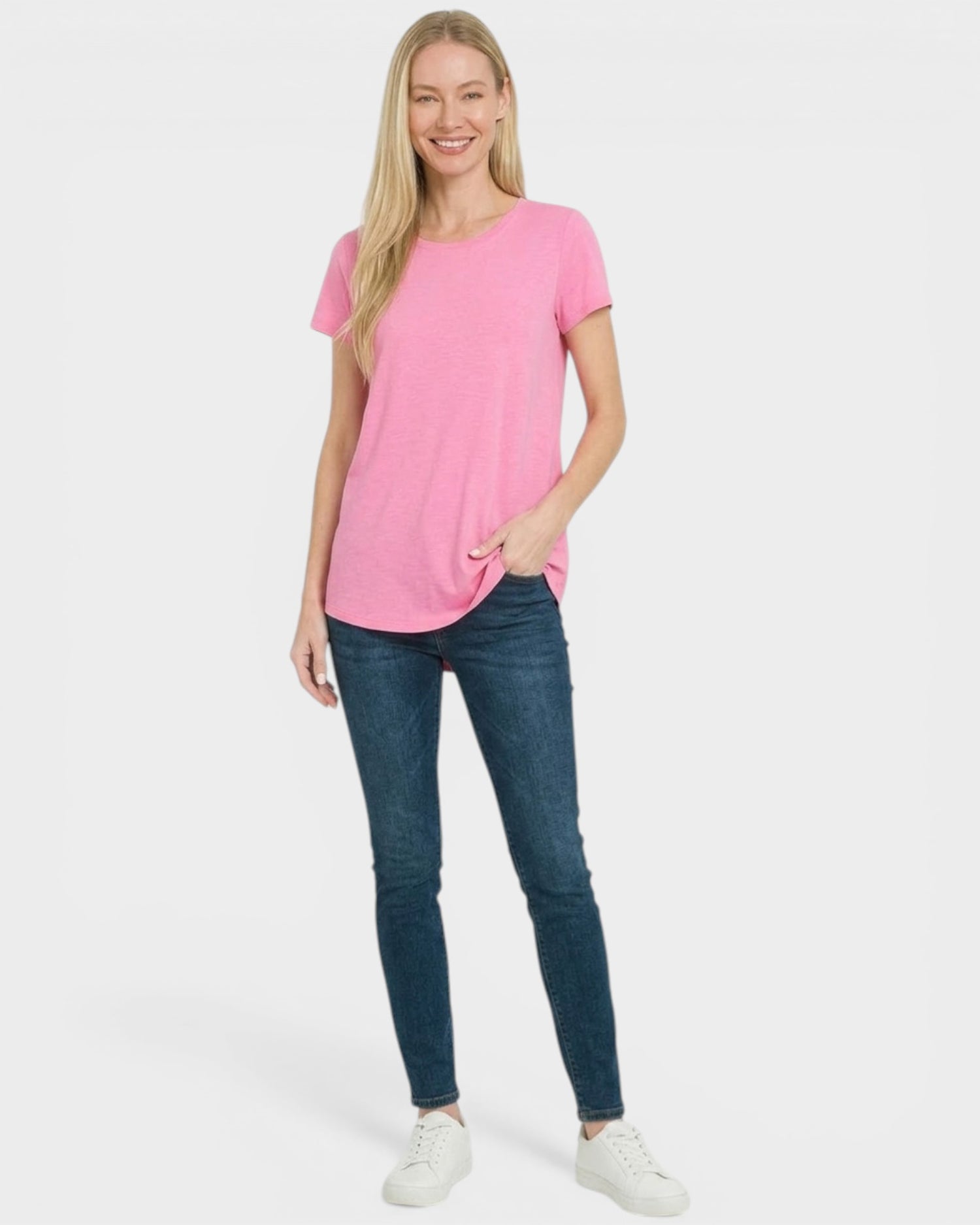 Woman wearing a pink t-shirt and blue jeans on a white background