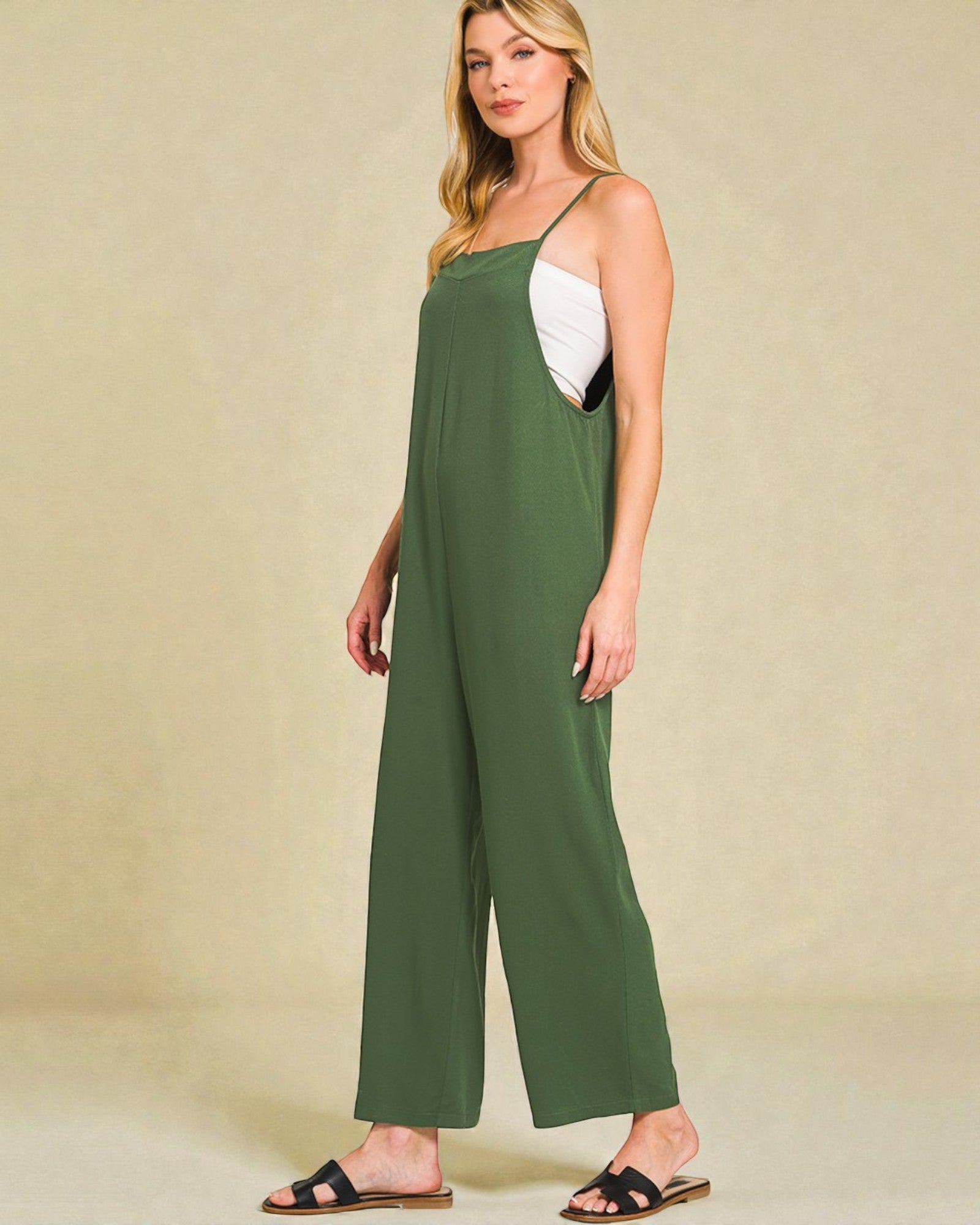 Woman wearing a green jumpsuit with a beige background