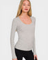Woman wearing a gray long-sleeve top against a white background
