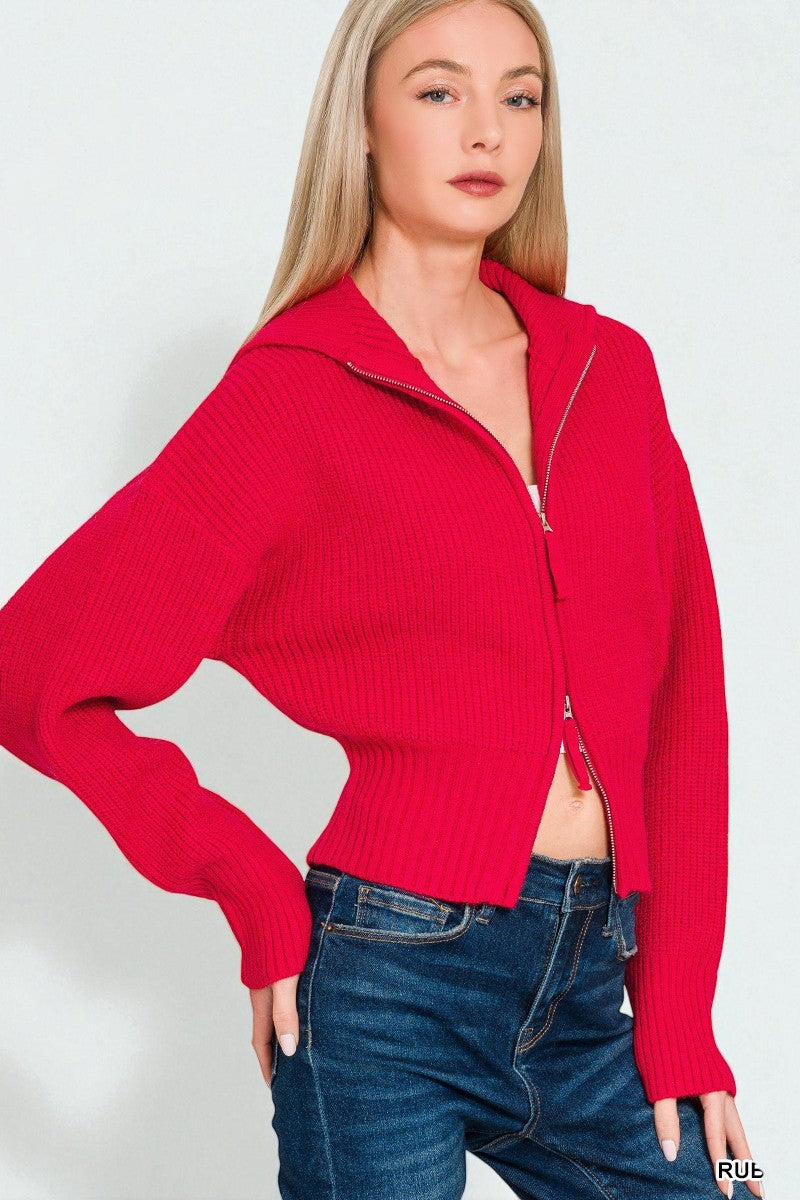 Woman wearing a red zip-up sweater and blue jeans on a white background