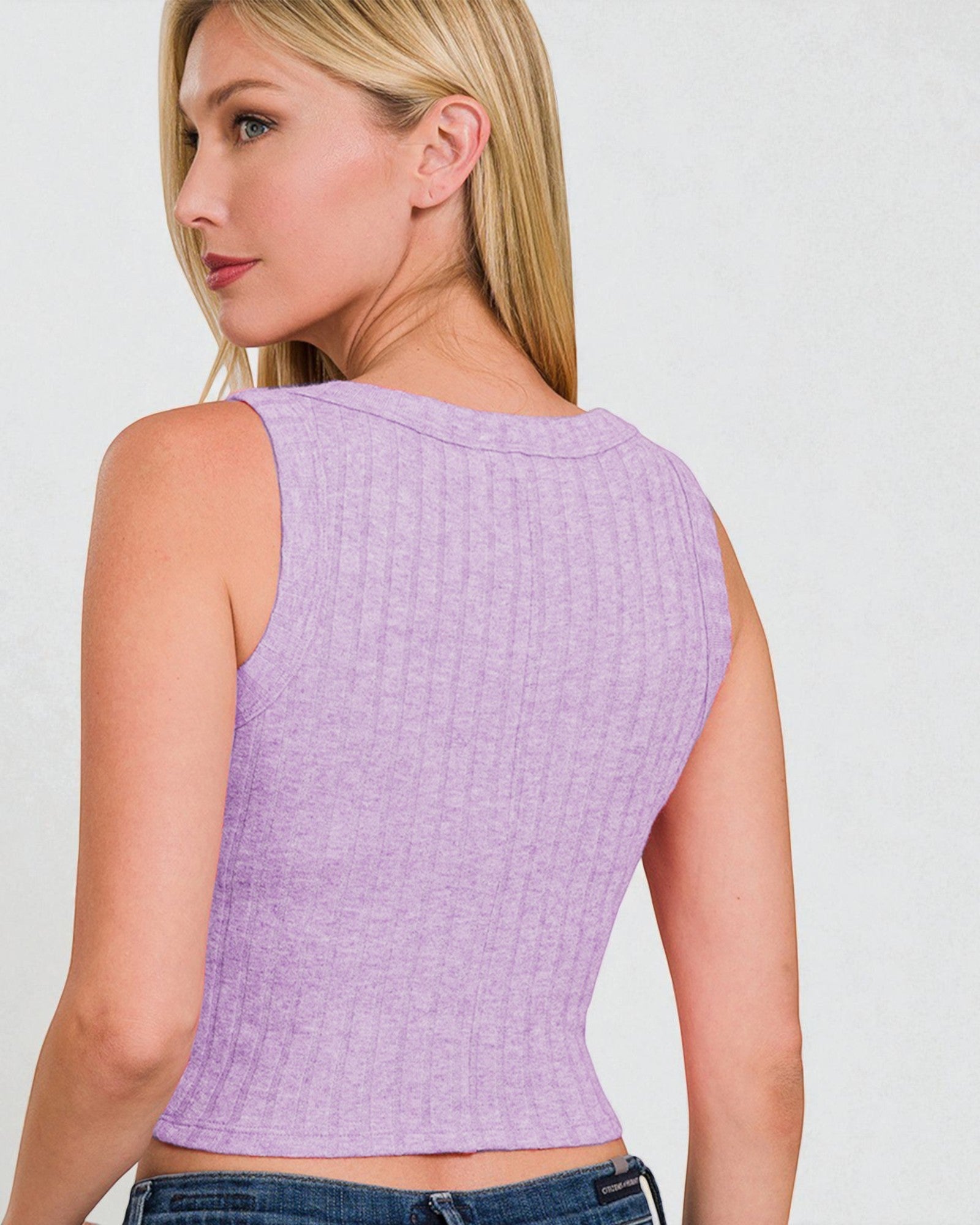 Woman wearing a light purple textured sleeveless top against a plain background