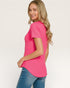 Woman wearing a bright pink t-shirt and blue jeans on a white background