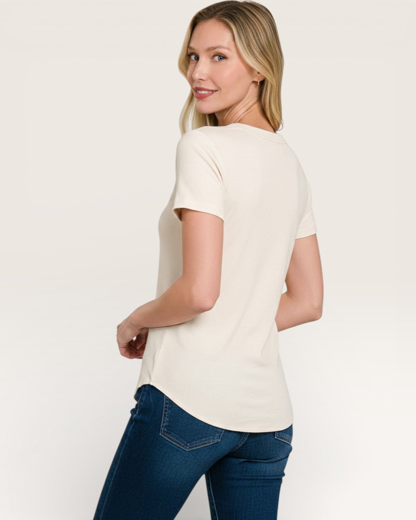 Woman wearing a white t-shirt and blue jeans on a plain background