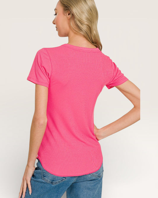 Woman wearing a bright pink t-shirt and blue jeans on a plain background