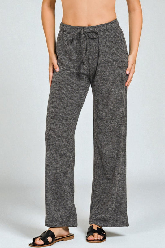 Person wearing dark gray wide-leg pants on a light gray background